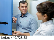 male seller assisting woman in choosing door in houseware shop. Стоковое фото, агентство Ingram Publishing / Фотобанк Лори