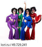 A group of girls in colorful flared suits and afro wigs pose against a white background. Disco style from the eighties or seventies. Стоковое фото, фотограф Лазаренко Светлана / Фотобанк Лори