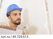 contractor on renovation site looking at notes scribbled on wall. Стоковое фото, агентство Ingram Publishing / Фотобанк Лори
