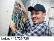 portrait of a smiling young computer technician with cables. Стоковое фото, агентство Ingram Publishing / Фотобанк Лори