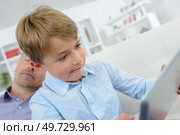 a sneaky kid using a tablet. Стоковое фото, агентство Ingram Publishing / Фотобанк Лори