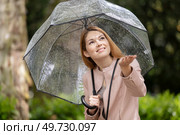woman rainy girl standing with transparent umbrella stretching arm. Стоковое фото, агентство Ingram Publishing / Фотобанк Лори