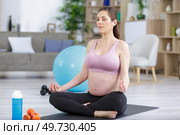 young pregnant woman meditating in lotus position. Стоковое фото, агентство Ingram Publishing / Фотобанк Лори