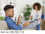 man watching tv and woman ironing clothes. Стоковое фото, агентство Ingram Publishing / Фотобанк Лори
