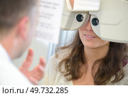 female patient looking through phoropter during eye exam. Стоковое фото, агентство Ingram Publishing / Фотобанк Лори