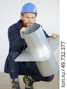 man holding a metal chimney flue. Стоковое фото, агентство Ingram Publishing / Фотобанк Лори