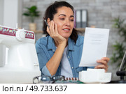 cheerful woman is reading sewing machine instructions. Стоковое фото, агентство Ingram Publishing / Фотобанк Лори