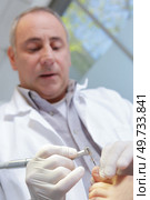 podiatrist assists patient with chiropody. Стоковое фото, агентство Ingram Publishing / Фотобанк Лори