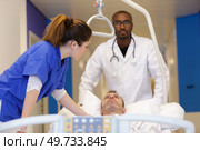 nurse and doctor carrying male patient on hospital gurney. Стоковое фото, агентство Ingram Publishing / Фотобанк Лори