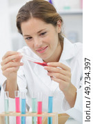 young happy female dropping red liquid substance into test tube. Стоковое фото, агентство Ingram Publishing / Фотобанк Лори