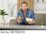 man eating popcorn on the sofa - studio shoot. Стоковое фото, агентство Ingram Publishing / Фотобанк Лори