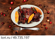 Chicken legs or drumsticks marinated in red wine, baked with orange and berries. Flat lay. Rustic style. Baked chicken legs with orange and berries. Стоковое фото, агентство Ingram Publishing / Фотобанк Лори