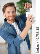 man screwing a device on the wall. Стоковое фото, агентство Ingram Publishing / Фотобанк Лори