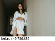 brown-haired girl in the morning in a bathrobe in the hotel corridor with a glass of white wine. Стоковое фото, агентство Ingram Publishing / Фотобанк Лори