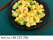 Vegan fresh pineapple and cucumber salad. Pineapple salad served on a black plate and chopstick.. Asian pineapple and cucumber salad. Стоковое фото, агентство Ingram Publishing / Фотобанк Лори