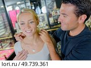couple looking at mirror when man trying necklace. Стоковое фото, агентство Ingram Publishing / Фотобанк Лори