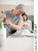 male plumber using plunger in kitchen sink. Стоковое фото, агентство Ingram Publishing / Фотобанк Лори
