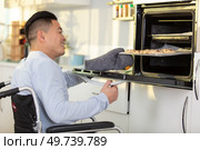 positive man in a wheelchair using the oven. Стоковое фото, агентство Ingram Publishing / Фотобанк Лори