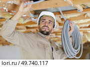 builder attaching a cables in the ceiling. Стоковое фото, агентство Ingram Publishing / Фотобанк Лори