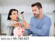 woman stopping husband from breaking piggy bank. Стоковое фото, агентство Ingram Publishing / Фотобанк Лори