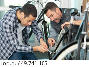 two guys examine bicycle in sport workshop. Стоковое фото, агентство Ingram Publishing / Фотобанк Лори