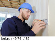 young male builder stripping wallpaper with a scraper. Стоковое фото, агентство Ingram Publishing / Фотобанк Лори