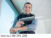 happy man with silicone sealant and caulking gun in hand. Стоковое фото, агентство Ingram Publishing / Фотобанк Лори