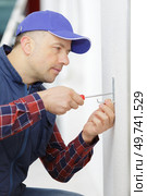 man screwing a hook on the wall. Стоковое фото, агентство Ingram Publishing / Фотобанк Лори