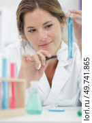 young woman looks at a flask through a magnifying glass. Стоковое фото, агентство Ingram Publishing / Фотобанк Лори