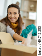 happy woman unpacking box in new home. Стоковое фото, агентство Ingram Publishing / Фотобанк Лори