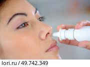 Woman using a nose spray. Стоковое фото, агентство Ingram Publishing / Фотобанк Лори