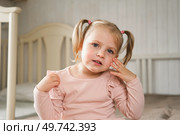 Little Girl joking sticking tongue out with silly expression. Child making face. Funny foolishness portrait of baby girl laughing in bedroom. Adorable Caucasian kid doing crazy comical gesture at home. Стоковое фото, фотограф Марина Демидюк / Фотобанк Лори