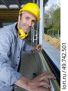 happy construction worker installing window indoors. Стоковое фото, агентство Ingram Publishing / Фотобанк Лори