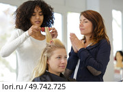 trainee hairdresser practicing using curlers. Стоковое фото, агентство Ingram Publishing / Фотобанк Лори