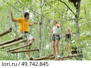 visitors in adventure park clambering with ropes. Стоковое фото, агентство Ingram Publishing / Фотобанк Лори