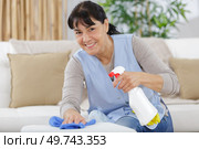 smiling woman spraying cleaning liquid on a table. Стоковое фото, агентство Ingram Publishing / Фотобанк Лори