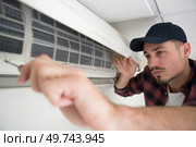 portrait of a young man adjusting air conditioning system. Стоковое фото, агентство Ingram Publishing / Фотобанк Лори
