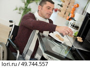 portrait of a man in a wheelchair by the oven. Стоковое фото, агентство Ingram Publishing / Фотобанк Лори