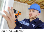 workman using cordless drill while installing pvc windows. Стоковое фото, агентство Ingram Publishing / Фотобанк Лори