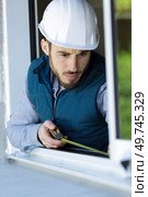 man measuring window prior to installation of roller shutter outdoors. Стоковое фото, агентство Ingram Publishing / Фотобанк Лори