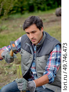 man hammering wooden stake into ground. Стоковое фото, агентство Ingram Publishing / Фотобанк Лори