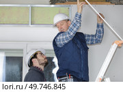 Contractor on stepladder talking to colleague on the ground. Стоковое фото, агентство Ingram Publishing / Фотобанк Лори