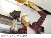 a licensed master checking a hole in the ceiling. Стоковое фото, агентство Ingram Publishing / Фотобанк Лори
