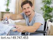 disabled man on wheelchair ironing clothing. Стоковое фото, агентство Ingram Publishing / Фотобанк Лори