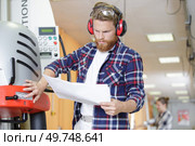factory operative with paperwork setting up machinery. Стоковое фото, агентство Ingram Publishing / Фотобанк Лори