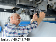 senior mechanic checking underneath vehicle. Стоковое фото, агентство Ingram Publishing / Фотобанк Лори