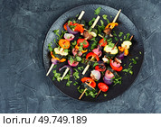 Delicious shashlik of fresh roasted vegetables on wooden skewers on on a concrete kitchen table. Space for text.. Grilled vegetables on skewers, BBQ. Стоковое фото, агентство Ingram Publishing / Фотобанк Лори