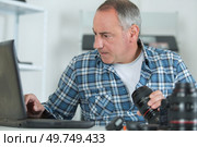 man repairing a dslr and looking for help on internet. Стоковое фото, агентство Ingram Publishing / Фотобанк Лори