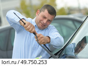 man picking up windscreen wiper. Стоковое фото, агентство Ingram Publishing / Фотобанк Лори