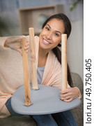 woman screwing leg back on to a small table. Стоковое фото, агентство Ingram Publishing / Фотобанк Лори